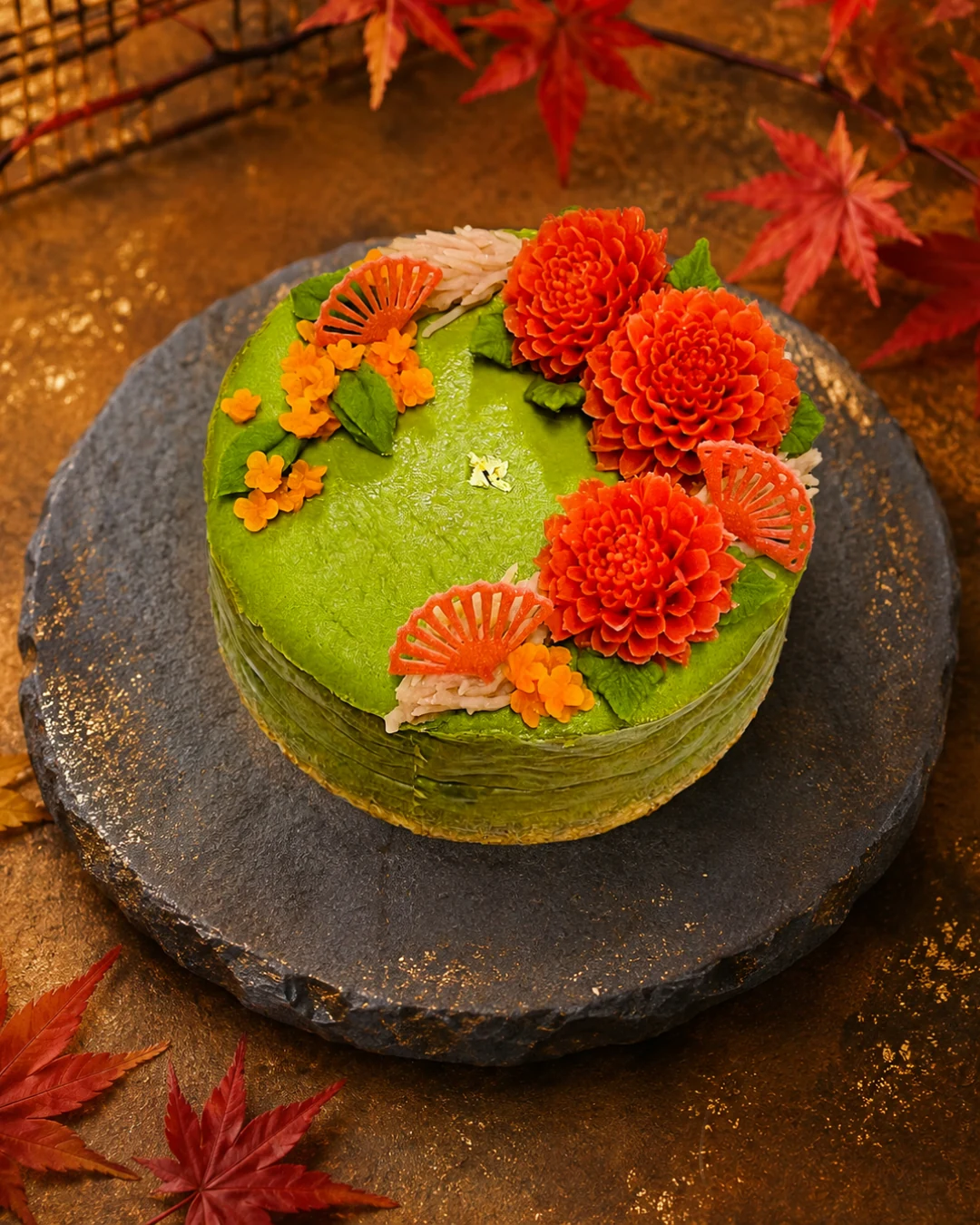紅葉と橙色の花を飾った抹茶色のケーキ