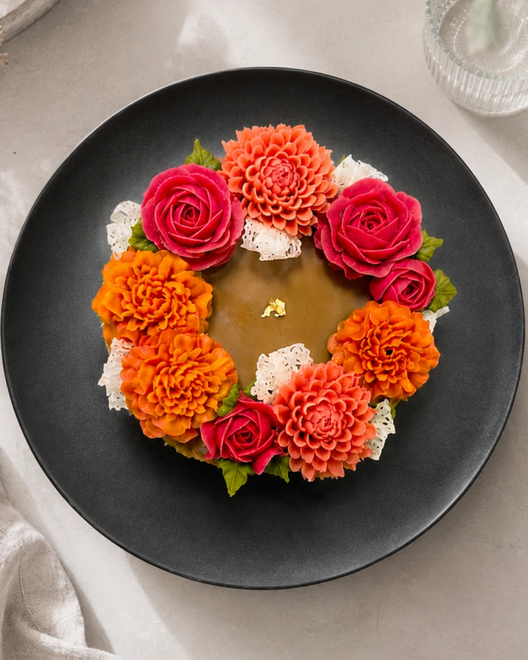 深いボルドーの花々を載せたケーキの制作風景